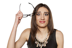 confused young woman with glasses in her hand
